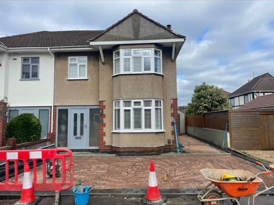 Front garden of a 1930s pebbledash semi excavated to bare sub-base, ready for a new driveway