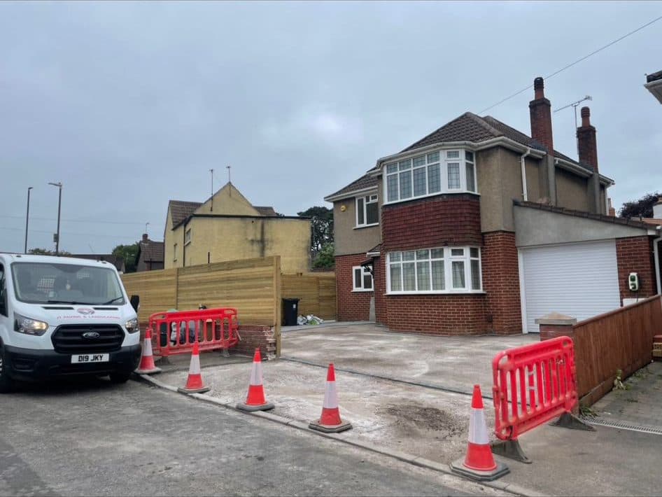 Detached house driveway during construction with a compacted base and safety barriers