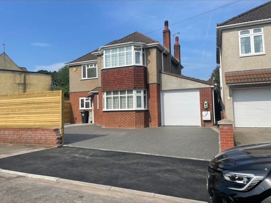 A finished resin-bound driveway in the sun at a rendered detached house